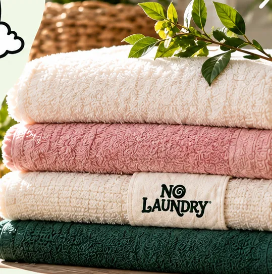 A stack of folded NoLaundry towels topped with a sprig of green leaves